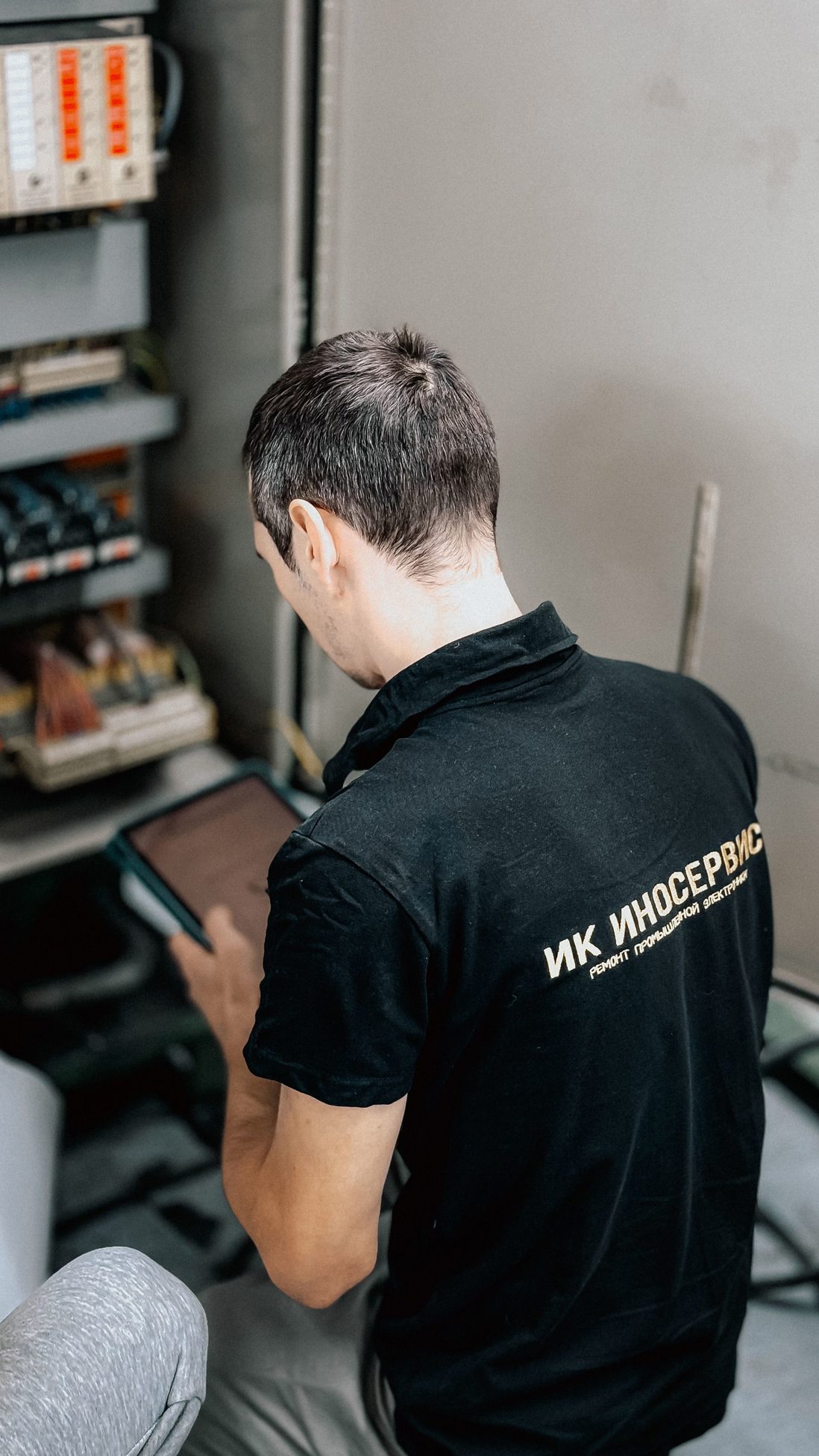 Electrician checking an electrical panel while using a tablet, a realistic scene for whole-home energy monitor installation.
